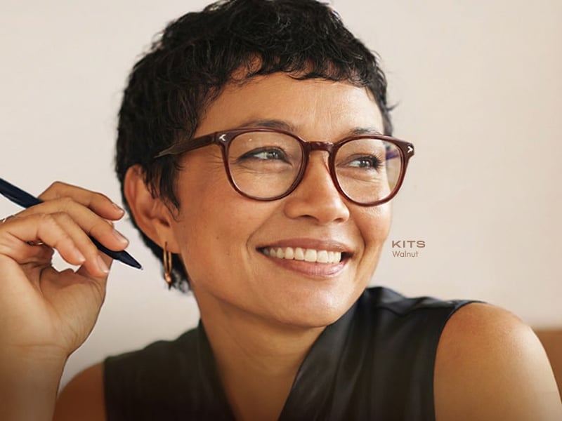 Person wearing KITS reader glasses while holding a pen