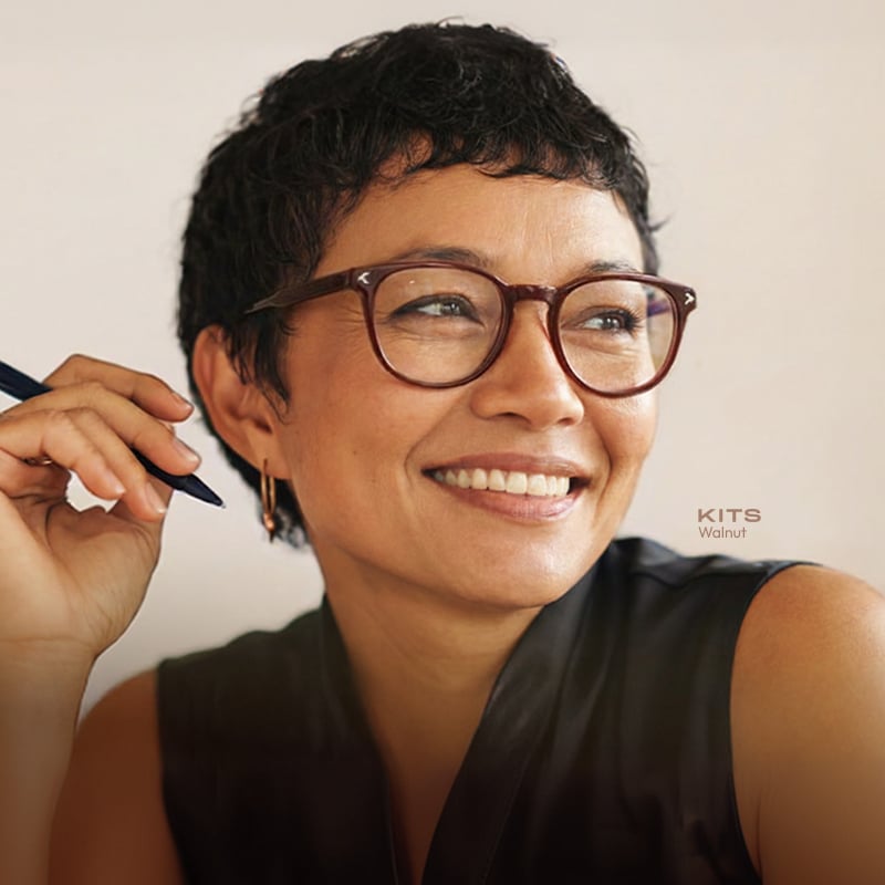 Person wearing KITS reader glasses while holding a pen